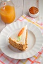 Slice of carrot cake Pastel de zanahoria with icing and marzipan carrot on white background with carrot juice